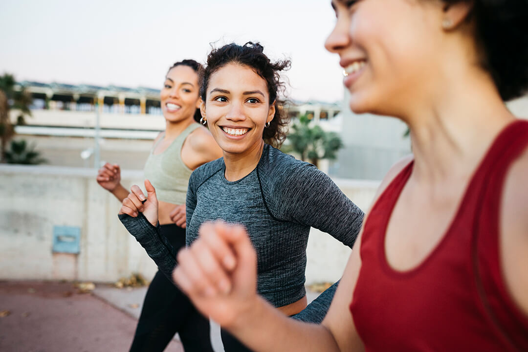 Group of three women jogging and smiling